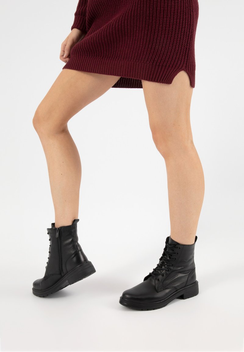 Schwarze Leder-Stiefeletten mit rundem Zehenbereich, Schnürung vorne und Reißverschluss an der Seite. Die Sohle ist dick und mit profiliertem Profil für besseren Halt versehen.