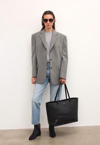 Szary, oversize'owy blazer, szara koszula, jasnoniebieskie dżinsy proste, czarna torba na ramię oraz czarne teksturowane botki za kostkę w wzór zebry.