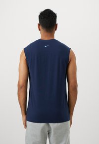 Marineblå ærmeløs skjorte med rund halsudskæring, lavet af blødt stof, med et lille lyseblåt Nike-logo på den øverste ryg.