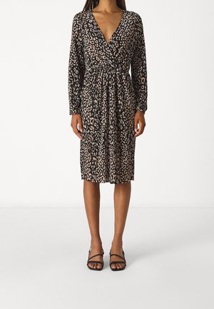 Schwarzes Kleid mit Leopardenmuster, langen Ärmeln, tiefem V-Ausschnitt, tailliertem Schnitt und knielangem Saum; kombiniert mit schwarzen Riemchensandalen.