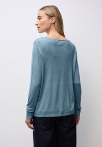 Maglione di maglia azzurro chiaro a maniche lunghe con vestibilità rilassata e scollatura ampia. Texture morbida, polsini e orlo a coste, design minimalista.