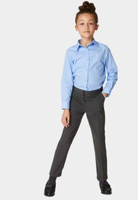 Helles blaues Langarm-Hemd mit Knopfleiste, kombiniert mit grauen, maßgeschneiderten Hosen. Das Outfit hat eine schlanke Passform mit einer glatten Textur und dunklen Schuhen.