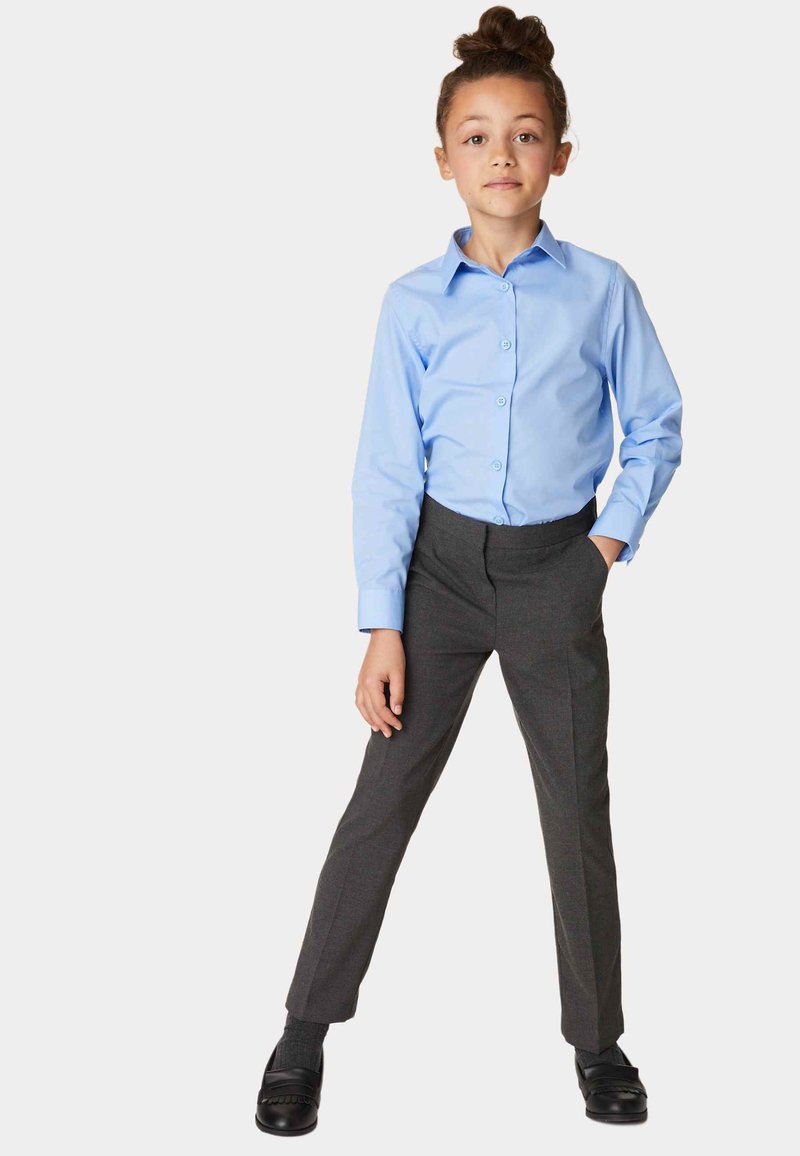 Helles blaues Langarm-Hemd mit Knopfleiste, kombiniert mit grauen, maßgeschneiderten Hosen. Das Outfit hat eine schlanke Passform mit einer glatten Textur und dunklen Schuhen.