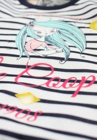 T-shirt en coton à rayures horizontales noires et blanches avec une fille dessin animé colorée, du texte rose et des formes accentuées jaunes.