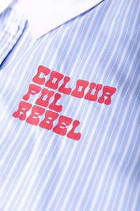 Lichtblauw gestreept overhemd met een witte kraag, voorzien van rode blokletters "COLOURFUL REBEL" en een zachte katoentextuur.