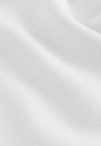 Tissu blanc lisse avec des plis doux et une texture fine de tissage visible, créant des ombres et des reflets subtils.