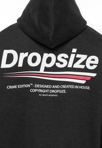 Sweat à capuche noir avec un grand texte blanc et rouge dans le dos. Le texte comprend "Dropsize" et "Crime Edition", avec d'autres détails de copyright.