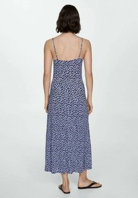 Robe longue à bretelles spaghetti, présentant un motif floral bleu et violet, coupe ample et texture lisse, atteignant la mi-mollet.