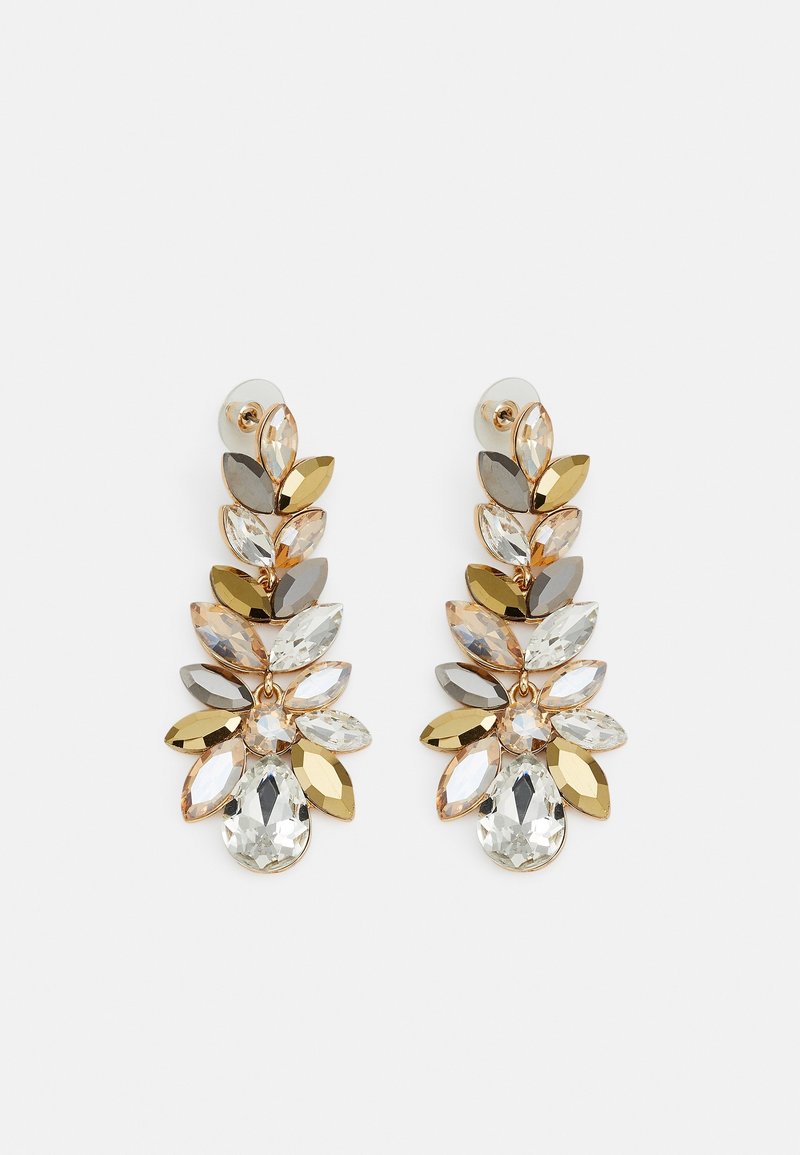 Longues boucles d'oreilles pendantes avec des cristaux en forme de feuilles dorées et argentées, disposés en motif floral sur fond blanc.