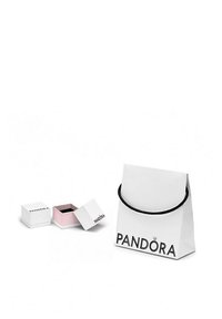 Busta di carta bianca con manico nero, con logo "PANDORA". Due piccole scatole regalo bianche, una con un interno rosa, parzialmente aperte.