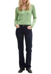 Haut à manches longues vert clair associé à un jean droit bleu foncé. Le haut a un col rond ; le jean dispose de poches avant et de coutures.