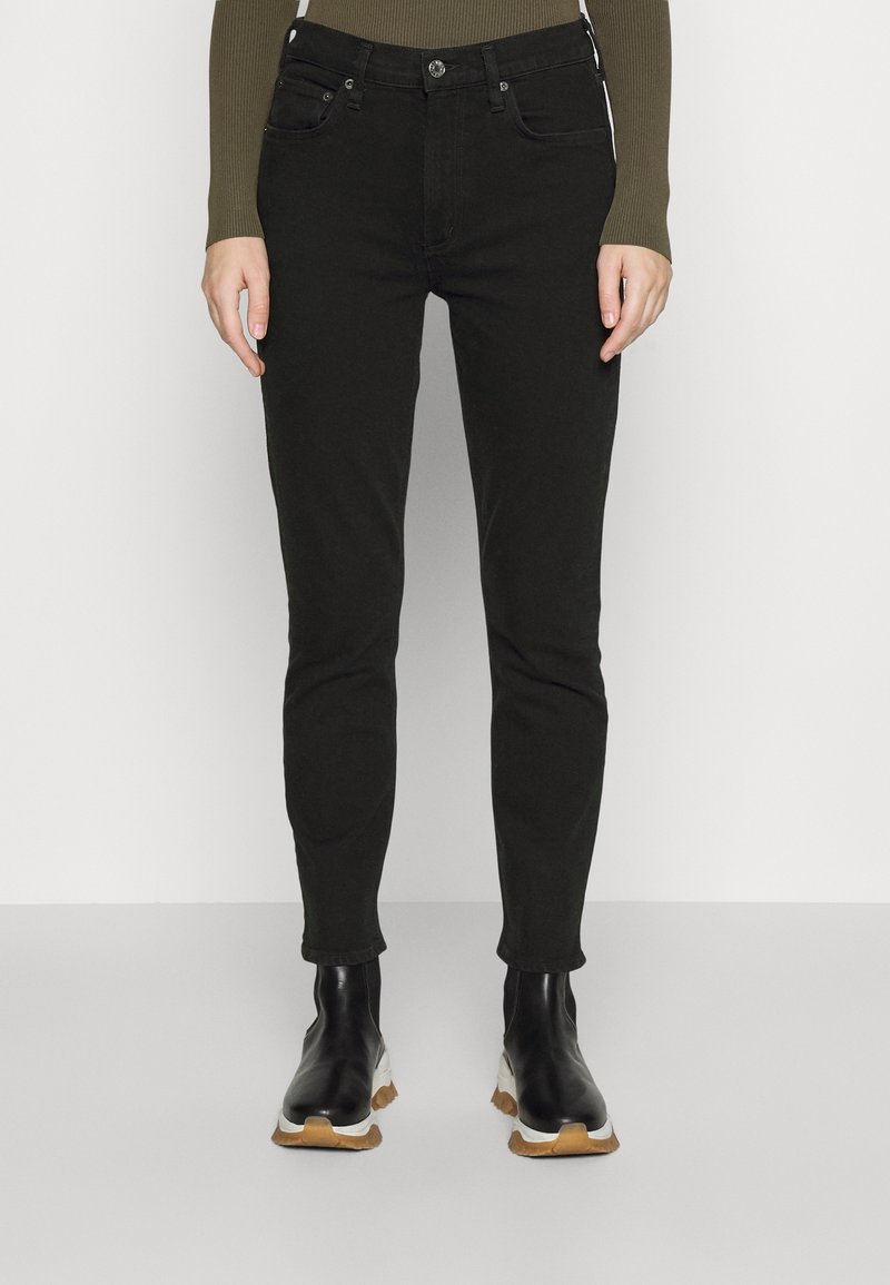 Jeans skinnies negros con cinco bolsillos, cierre de botón y cremallera. Llevados con botas de tobillo negras con suela texturizada y acentos blancos.