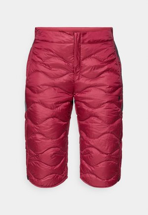 Pantalones cortos aislados rojos con un diseño acolchado, que presentan patrones de olas redondeadas. Acentos negros en los laterales y cierre de cremallera elegante. Material ligero.