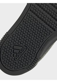 Černá podešev boty Adidas s kruhovým vzorem pro lepší přilnavost, logem Adidas a nápisem "Non-Marking" na boku podešve.