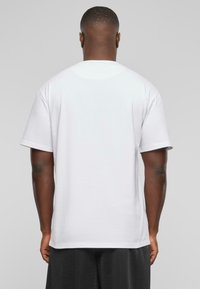 White t-shirt featuring short sleeves, a round neckline, and a loose fit, shown from the back with a smooth texture.