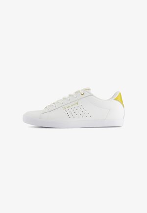 White sneakers with a smooth leather exterior, golden accent on the heel, perforated detailing on the side, and lace-up closure.