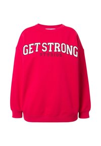 Sudadera rosa con texto en negrita y blanco que dice "GET STRONG STUDIOS", con un corte relajado y puños acanalados. Textura suave, diseño casual.