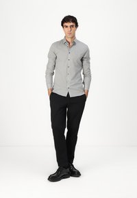 Camicia a quadri grigia e bianca con bottoni, a taglio slim, in cotone, abbinata a pantaloni neri e scarpe nere stringate.