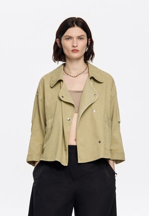 Giacca corta verde oliva con ampio colletto, grandi tasche frontali e bottoni a pressione. Realizzata in un tessuto leggero, presenta una vestibilità comoda.