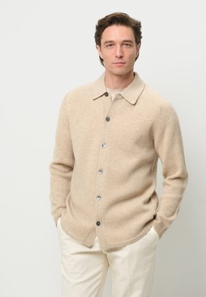 Beige ribbed cardigan with a collared neckline, front buttons, and side pockets. Textured knit fabric adds depth to the design.
