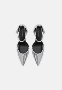 Zilveren pailletten puntige hakken met slingback ontwerp, voorzien van een dunne enkelband en contrasterende zwarte binnenvoering.