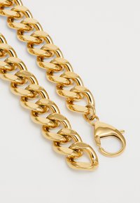 Gouden ketting met dikke, in elkaar grijpende schakels. Glad, glanzend oppervlak met een grote kreeftsluiting aan één uiteinde.