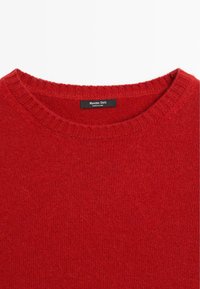 Maglione rosso a maglia con collo rotondo. Texture morbida, collo a coste e etichetta con il marchio all'interno. Realizzato in tessuto caldo e leggero.