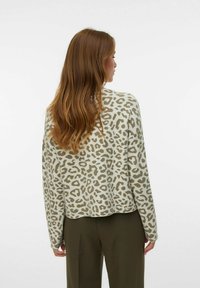 Pull en imprimé léopard vert et beige, avec des manches longues, une coupe décontractée et un ourlet rond au dos. Le tissu a l'air doux et texturé.
