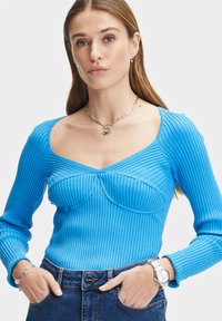 Blå randig långärmad topp med fyrkantig halsringning och figursydd bodice, kombinerad med högmidjade jeans. Har texturerad tyg och accentstyg.