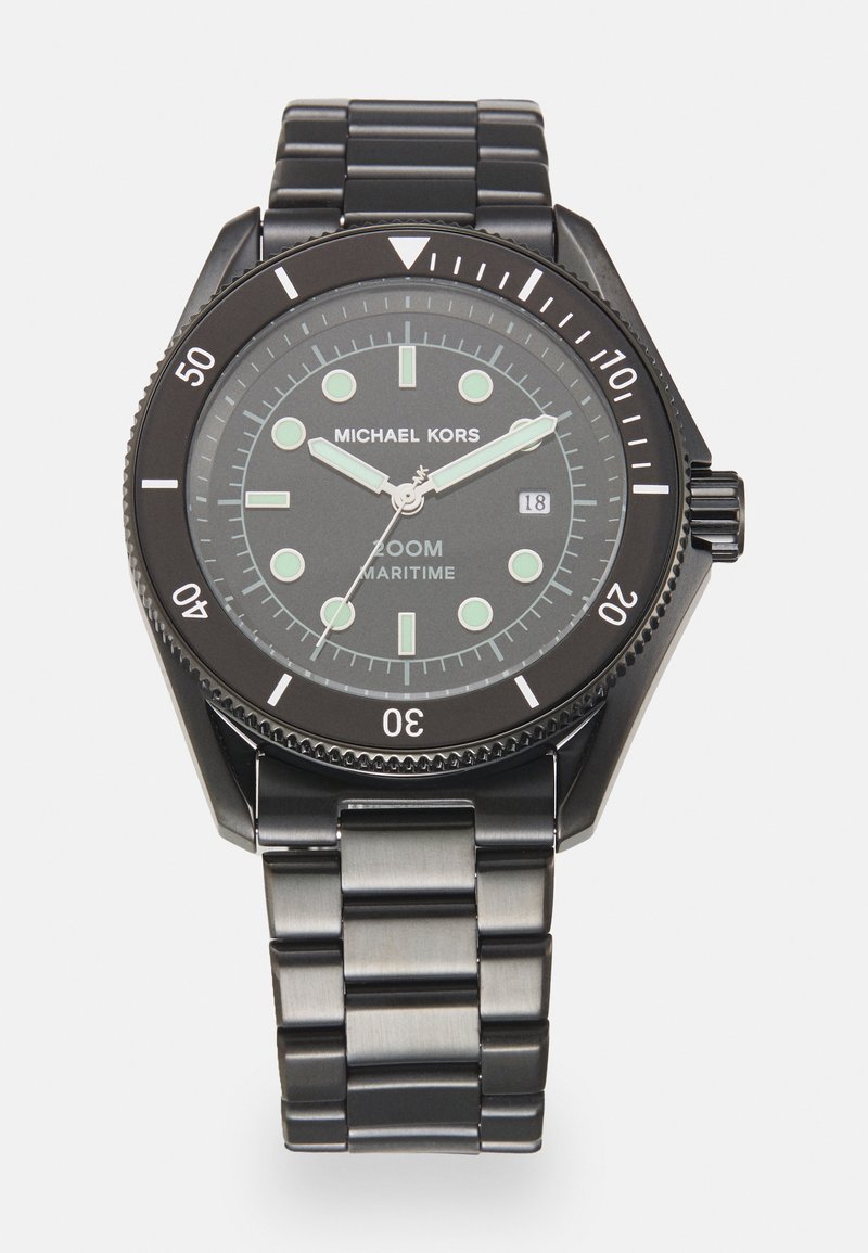 Reloj de acero inoxidable negro con una esfera redonda, marcadores luminescentes verdes y una pantalla de fecha. Presenta una pulsera y un bisel de metal.