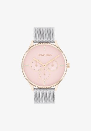 Calvin Klein watch with a rose gold bezel, pink dial, three sub-dials, and silver mesh strap. Features crystal accents on the bezel.