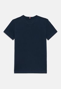 T-shirt de manga curta azul-marinho com decote redondo; apresenta detalhes de costura e um pequeno destaque em vermelho e branco no decote.