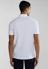 Witte polo met korte mouwen en een klassieke kraag, met een soepele textuur en een rechte zoom, gezien vanaf de achterkant.
