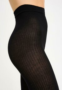 Leggings neri a costine realizzati in un materiale elastico e testurizzato, caratterizzati da una vita alta e una silhouette liscia e aderente.