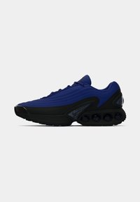 Blue athletic sneaker with textured upper, black sole, cushioned heel, and visible air bubble accents in sole. Includes lacing system.