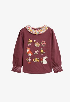 Camisa de manga larga color marrón con cuello estampado de flores y animales bordados que incluyen un zorro, un conejo, un erizo y flores en la parte posterior.