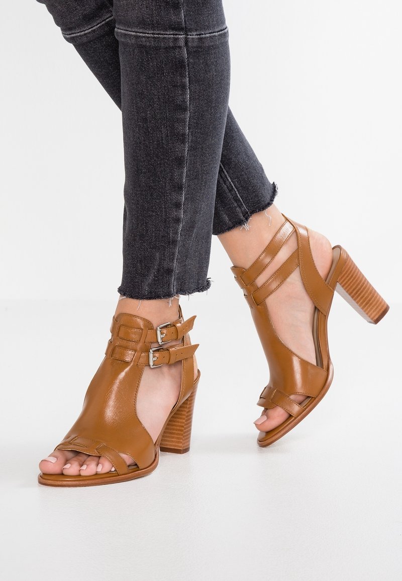 Ruske nahkakorkokengät, joissa on avointo kärki ja nilkkahihnat, varustettuna kahdella säädettävällä soljella ja teksturoidulla lohkokorkolla.