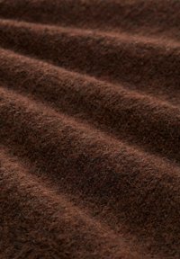 Brązowa wełniana tkanina o miękkiej, teksturowanej powierzchni, z subtelnymi odcieniami kolorów i luźno utkanymi włóknami, tworzącymi naturalny wygląd.