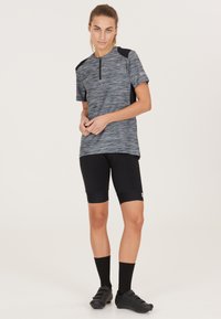 Grå och svart sporttröja med korta ärmar, dragkedja vid halsen; ihop med svarta cykelshorts och knähöga svarta strumpor. Svarta skor.