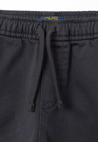 Dunkelgraue Shorts mit elastischem Bund und Kordelzug. Glatte Textur und schlichtes Design, mit einem Markenlabel am inneren Bund.