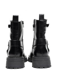 Czarne skórzane botki za kostkę z grubą gumową podeszwą, z zamkami błyskawicznymi i paskami po bokach, teksturowanym wykończeniem i wzmocnionymi obcasami.