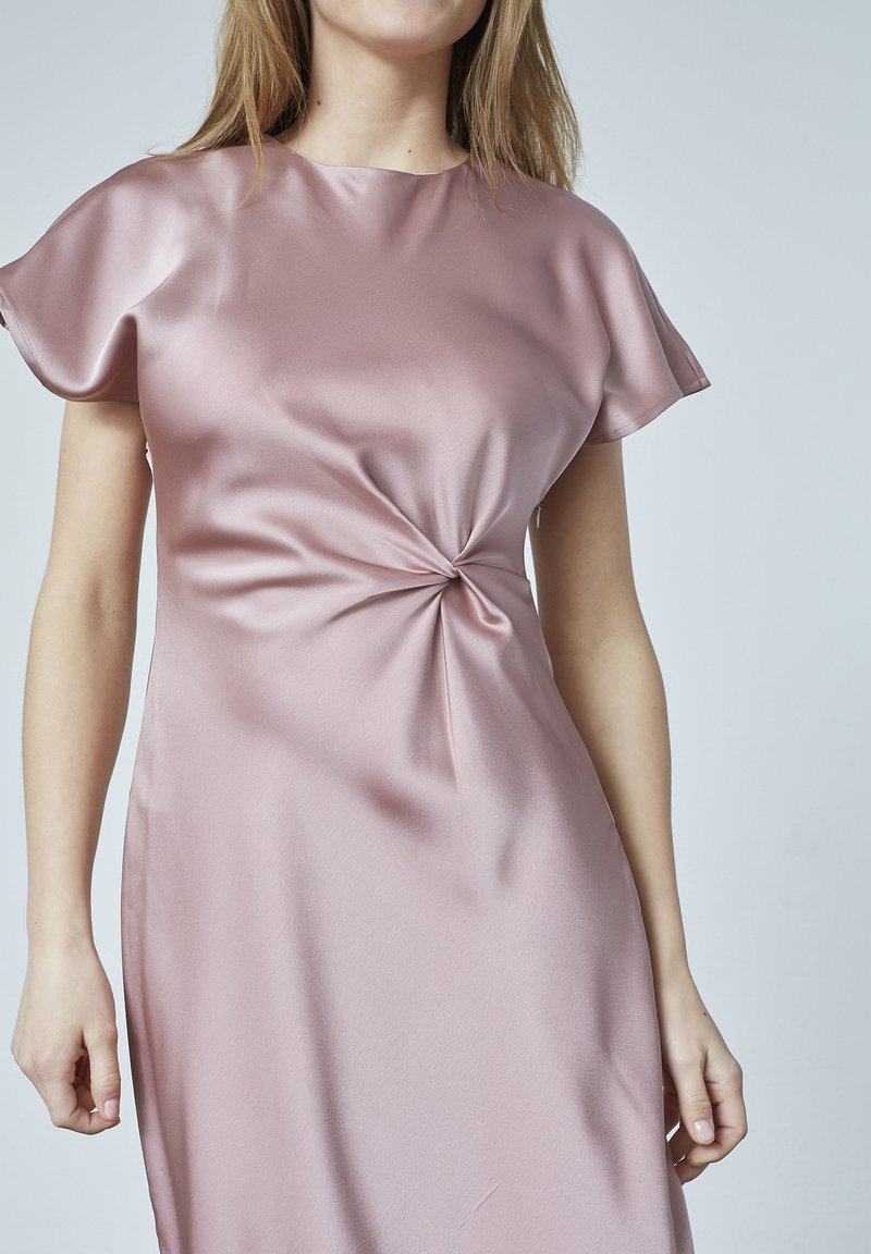 Satin rosa klänning med rund hals, korta fjäderlätta ärmar och en framåtvänd twistdetalj vid midjan. Slät textur och flödande design.