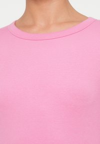 Ροζ ριμπ μπλουζάκι με στρογγυλή λαιμόκοψη, απαλό ύφασμα και εφαρμοστή γραμμή.