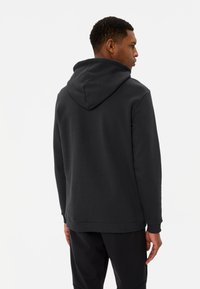 Felpa nera con cappuccio, dal tessuto solido, con polsini e orlo a costine e tasca a marsupio frontale. Design semplice e funzionale.