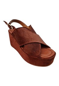 Sandalia de plataforma de ante marrón con diseño de tiras cruzadas, punta abierta, correa trasera ajustable y suela sólida parecida a la madera.