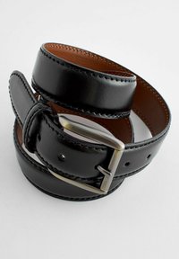 Ceinture en cuir noir avec une finition lisse, dotée d'une boucle en métal argenté et de coutures marron, enroulée soigneusement pour l'exposition.