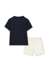 T-shirt en coton bleu marine à manches courtes et col rond, associé à un short en coton blanc avec une taille élastique.