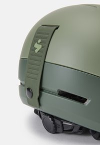 Casco verde oliva con una cinghia di regolazione testurizzata, manopola circolare alla base e feritoie di ventilazione per il passaggio dell'aria. Inclusi dettagli in gomma.