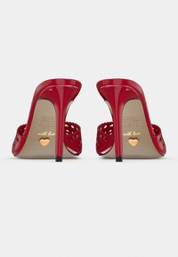 Sandales à talons hauts en cuir verni rouge avec design découpé, bouts pointus et talons aiguilles noirs. Accent en forme de cœur doré sur la semelle intérieure.