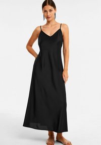 Schwarzes Maxikleid mit dünnen Trägern, einem V-Ausschnitt und einer fließenden Silhouette. Hergestellt aus leichtem Stoff mit einer glatten Textur.